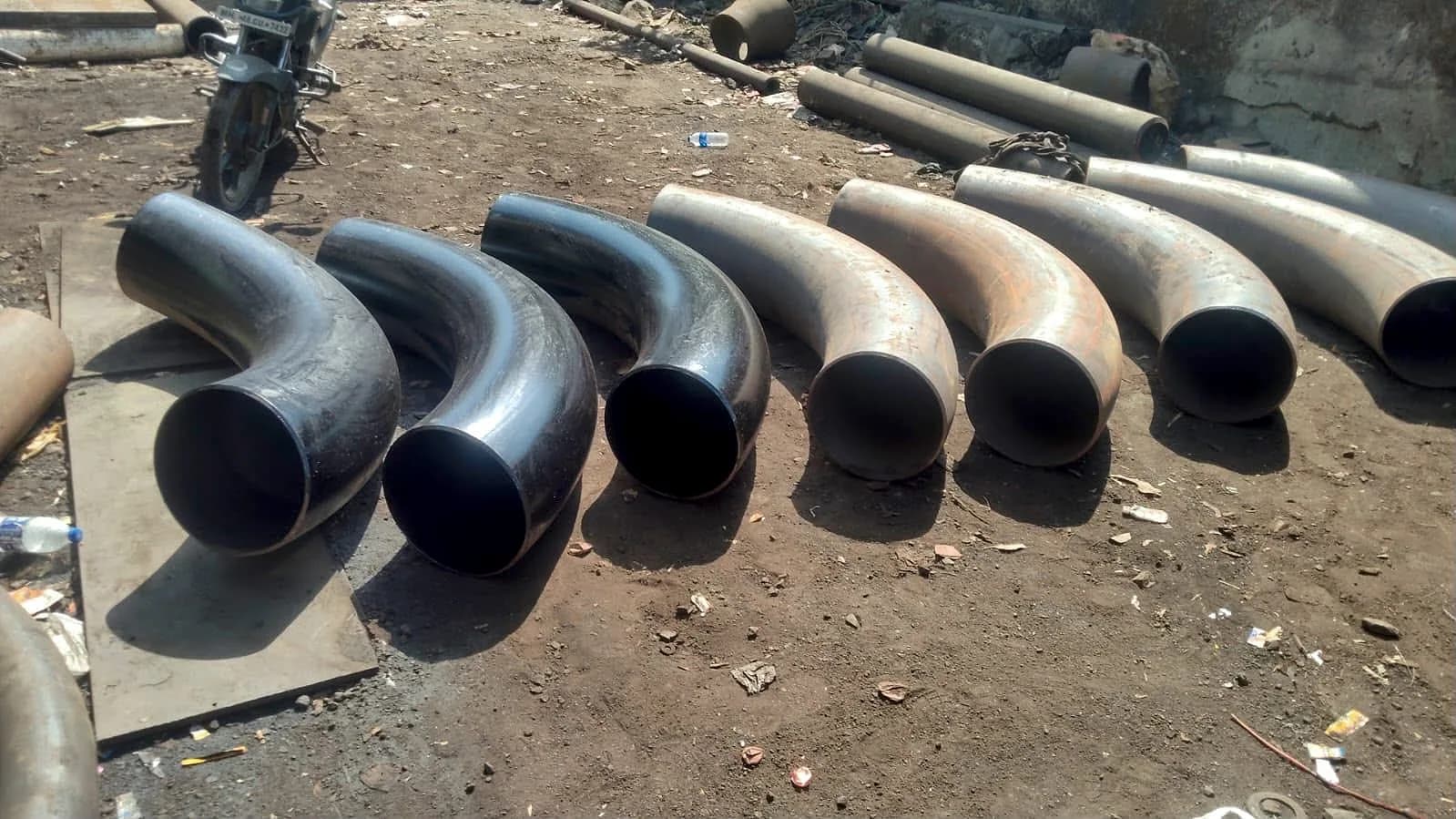 A row of 12 inch carbon steel pipe bends with a 10D radius laid side by side