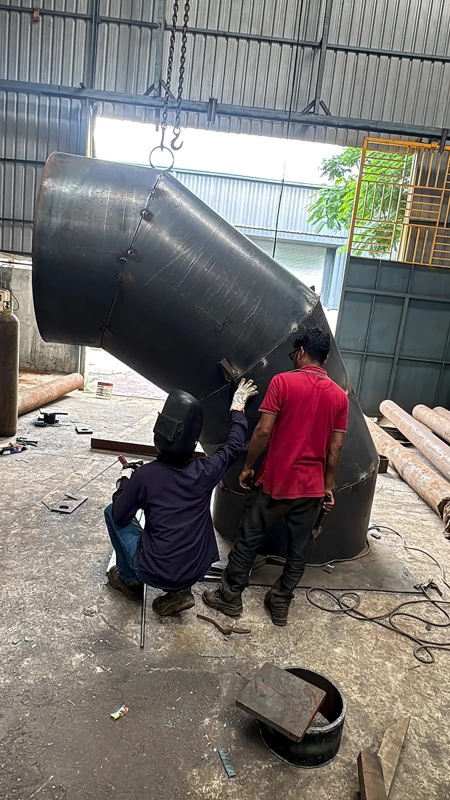 Two workers fitting up a large mitre bend standing upright in the works