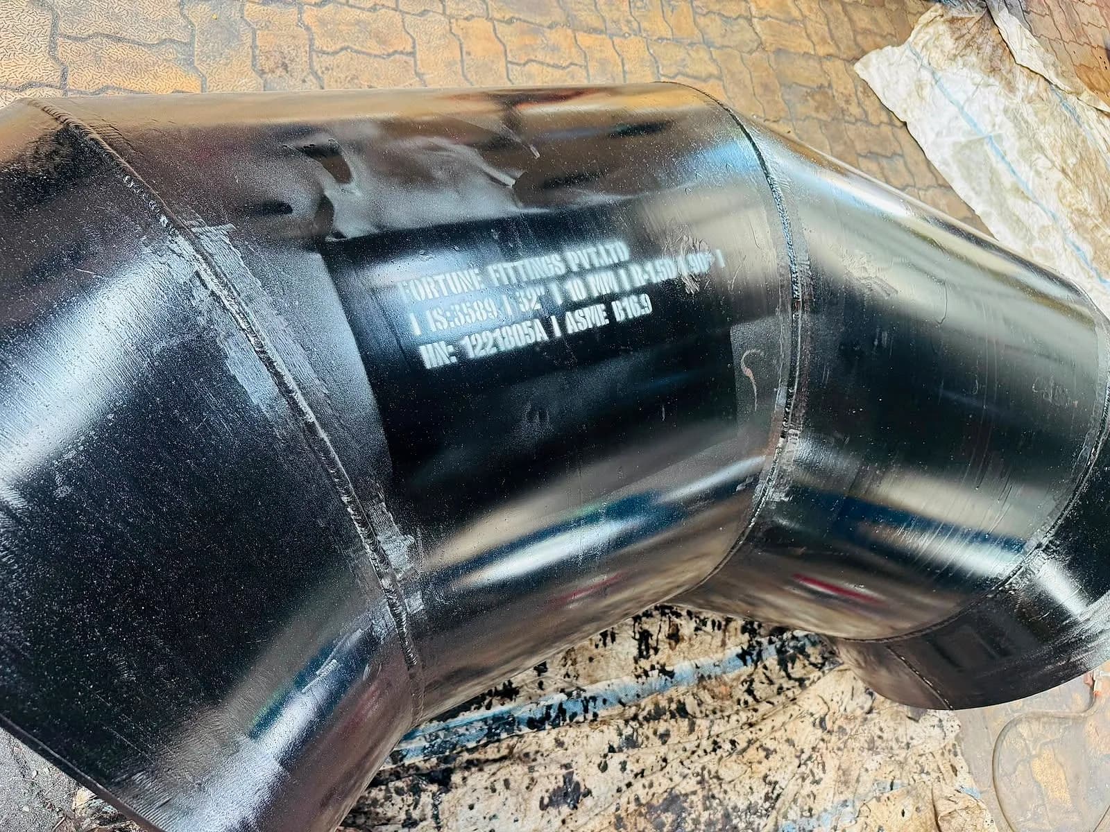 Close view of a black segmented mitre bend showing its circumferential welds and marking